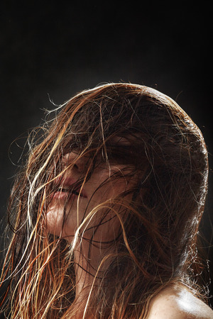 woman head with fluffy wet hair on black backgroundの写真素材