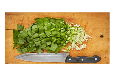 cutted wild garlic (Allium ursinum) on wood board isolated on whiteの写真素材