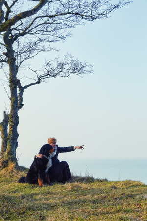 woman and dog under trees near seaの写真素材
