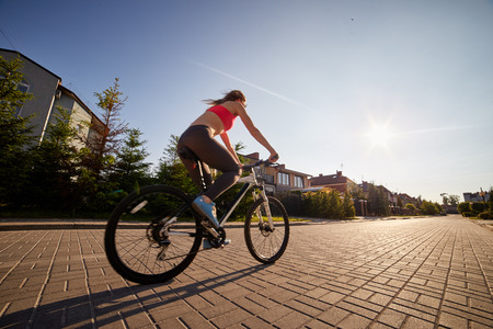 woman drives on bike in village at sunset, image with blur effectの写真素材