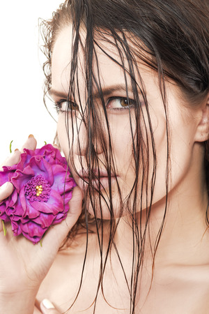 sensual woman with wet hairs and purple flower isolated on whiteの写真素材