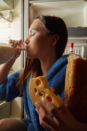 hungry woman drinking milk near refrigeratorの写真素材