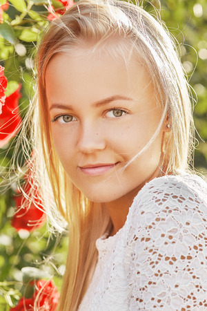 pretty blond girl looking at camera on flowers backgroundの写真素材