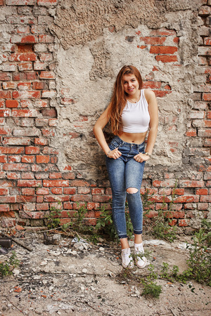 pretty woman in jeans posing on brick wall backgroundの写真素材