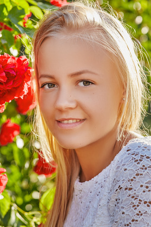 pretty blond girl looking at camera on flowers backgroundの写真素材
