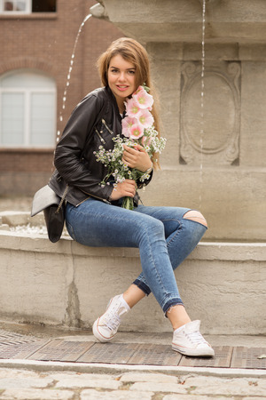 happy woman with flowers near fountain smilingの写真素材