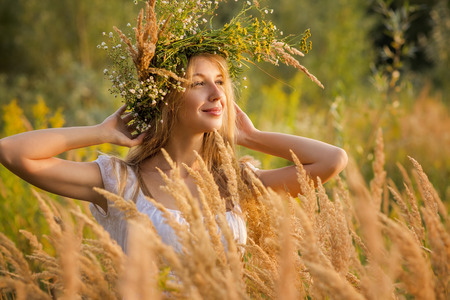 happy young woman in a wreath from a grassの写真素材
