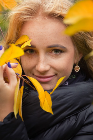 pretty happy woman with yellow leaves smilingの写真素材