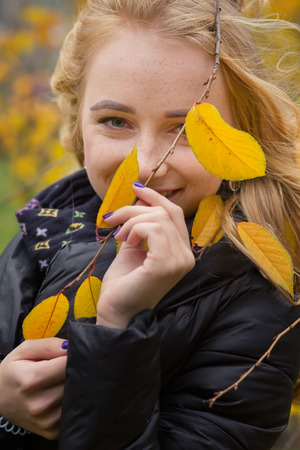 pretty happy woman with yellow leaves smilingの写真素材