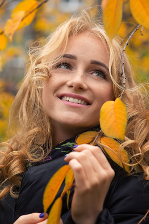 pretty happy woman with yellow leaves smilingの写真素材