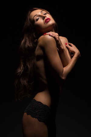 sensual aroused woman covering her body in darkの写真素材