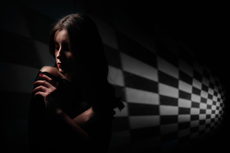 pensive woman with bare shoulder on dark background with copyspaceの写真素材