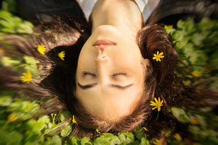 beautiful girl lying on grass with flowers, image with blur effectの写真素材