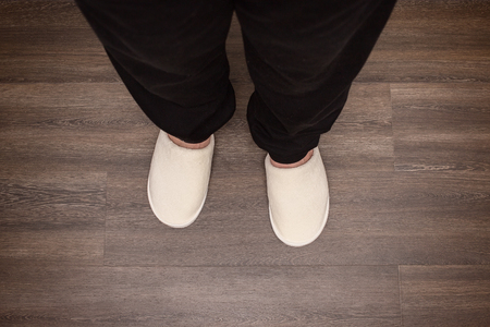 male legs in white slippers stand on parquetの写真素材