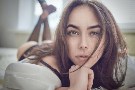 sensual girl lying looking at camera, toned imageの写真素材