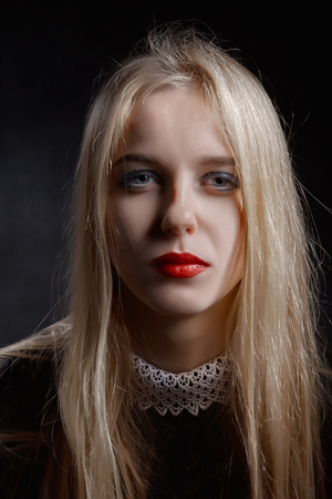 sad pensive blond girl on black backgroundの写真素材