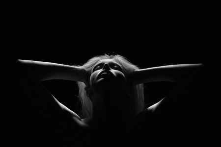 female silhouette with closed eyes in dark, monochrome imageの写真素材