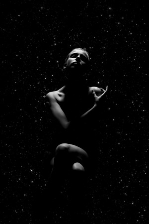 sad woman sitting on stars sky background, monochrome imageの写真素材