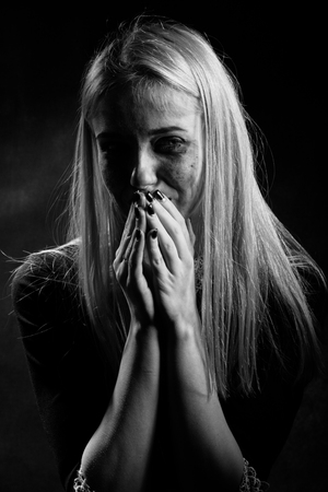 woman with smeared cosmetics crying on black background, monochromeの写真素材