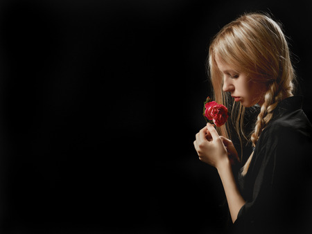 sensual blond girl with rose on black background with copyspaceの写真素材