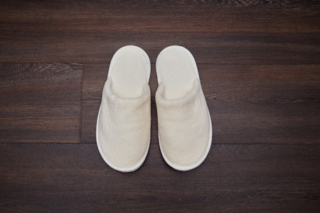 pair soft white slippers on wooden floorの写真素材