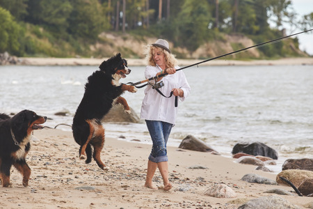 woman with her dogs on sea beach walkingの写真素材