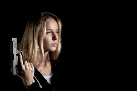 serious girl with gun on black background with copyspaceの写真素材