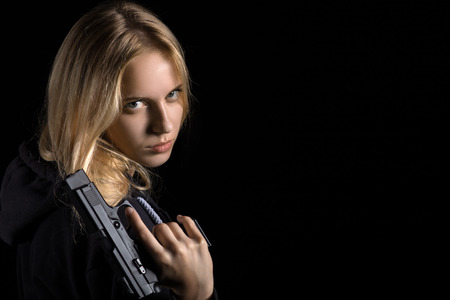 beautiful girl with gun on black background with copyspace
