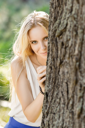 smiling girl looks out because of a treeの写真素材