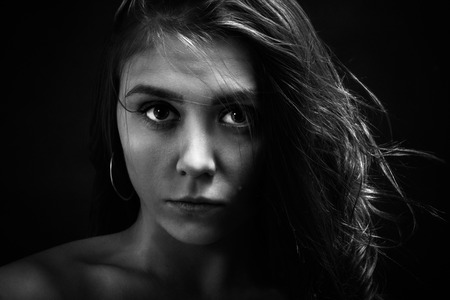 serious sad girl portrait on black background, monochromeの写真素材