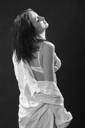 beautiful woman in white lingerie undressing on black background, monochromeの写真素材
