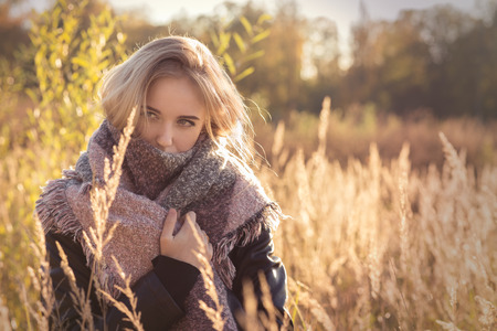 sad beautiful woman in dry grass at sunset, toned imageの写真素材
