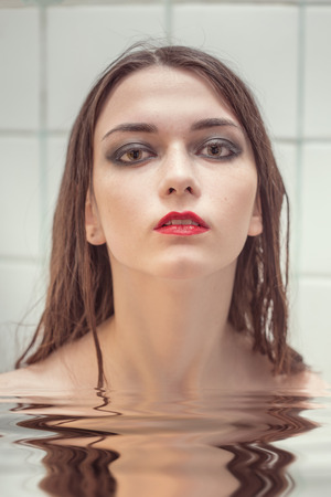 beautiful girl in water with reflections, toned imageの写真素材