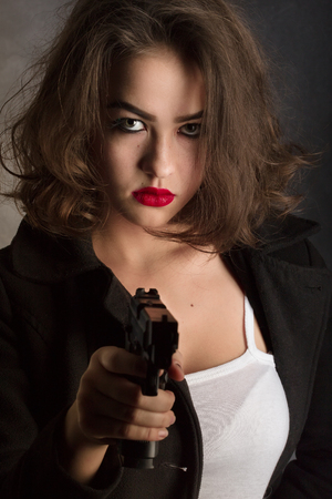 serious girl with gun aiming with gun on black backgroundの写真素材