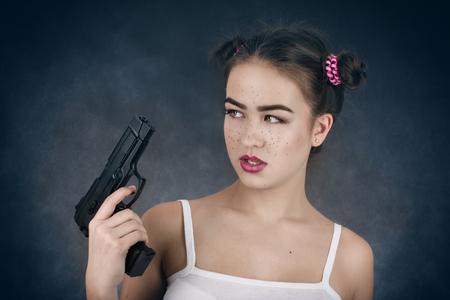 serious girl with gun on black backgroundの写真素材