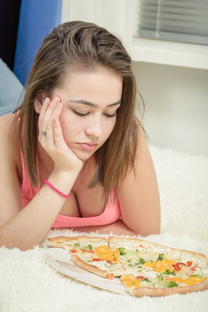 unhappy woman with pieces of pizza on white backgroundの写真素材