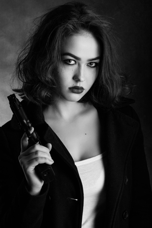 serious girl with gun on black background, monochromeの写真素材