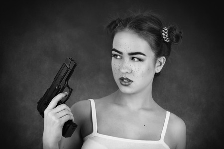serious girl with gun on black background, monochromeの写真素材