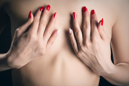 female hands covering beautiful small breasts closeupの写真素材