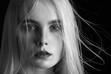 sensual blond girl with flying hair portrait on black background, monochromeの写真素材