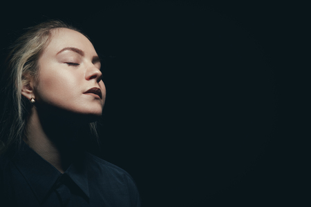 sad woman with closed eyes on black backgroundの写真素材