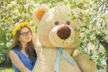 happy girl with teddy bear in spring flowersの写真素材