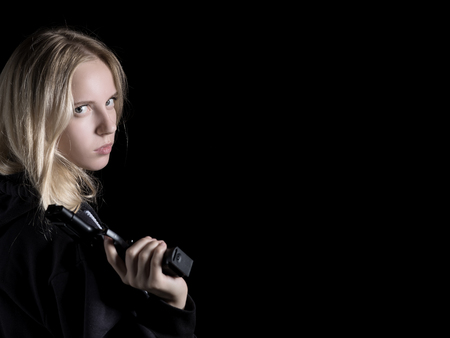 serious girl with gun on black background with copy spaceの写真素材