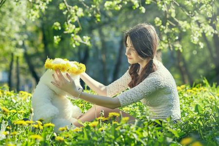 girl plays with teddy bear on dandelion meadow, toned imageの写真素材