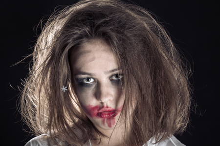 pretty fun crazy girl with fluffy hair and smeared cosmetics on black backgroundの写真素材