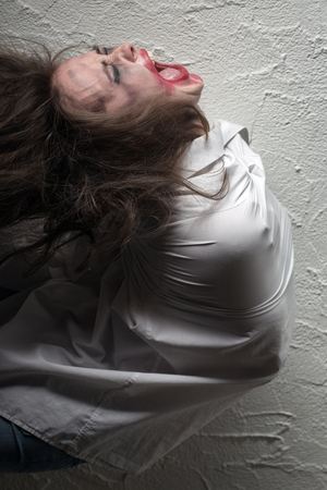 screaming crazy woman with flying hair in straitjacketの写真素材