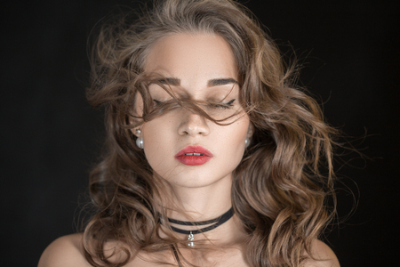 luxury woman with curly long hair, closed eyes on black backgroundの写真素材