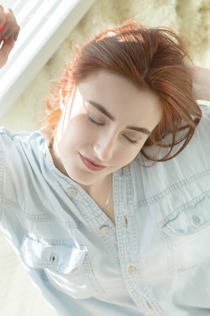 sensual beautiful woman sitting at sofa with blinds light in sunlightの写真素材
