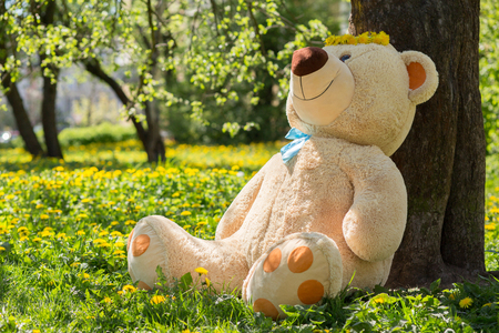 big teddy bear sitting under blowing treesの写真素材