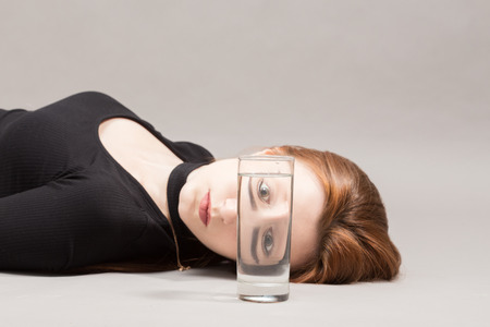sad girl and glass with water on gray background with copy spaceの写真素材